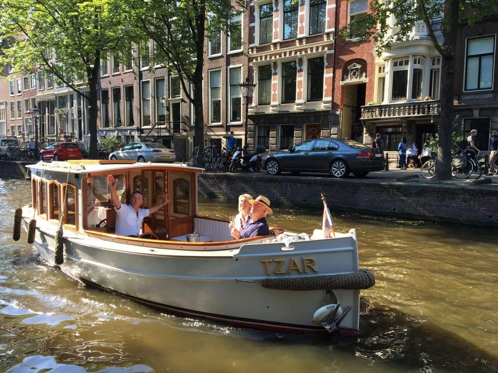 Los turistas están disfrutando de la excursión en barco por el té en Amsterdam.