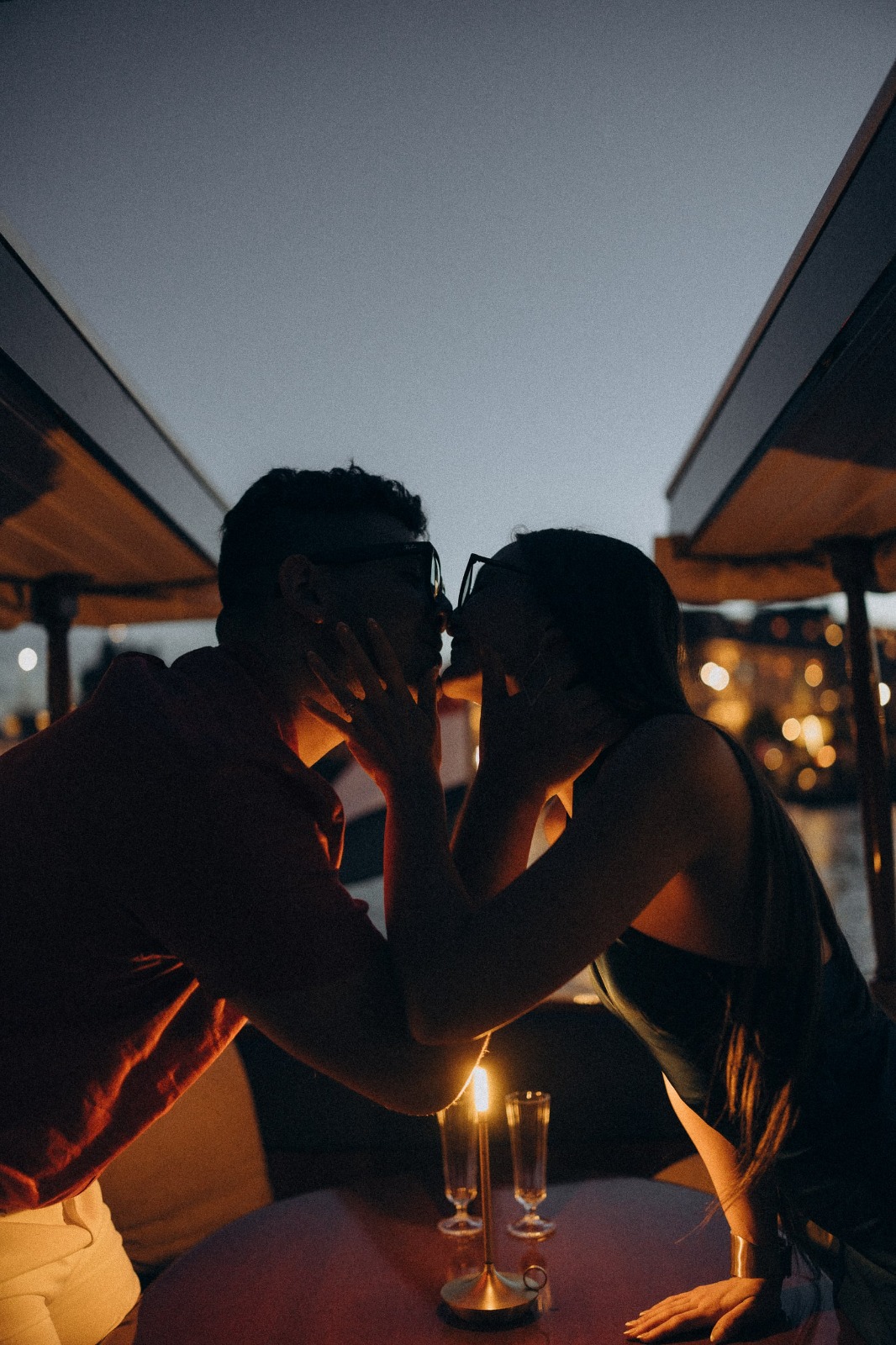 Pareja bes&aacute;ndose a la luz de las velas en un crucero privado al atardecer en &Aacute;msterdam