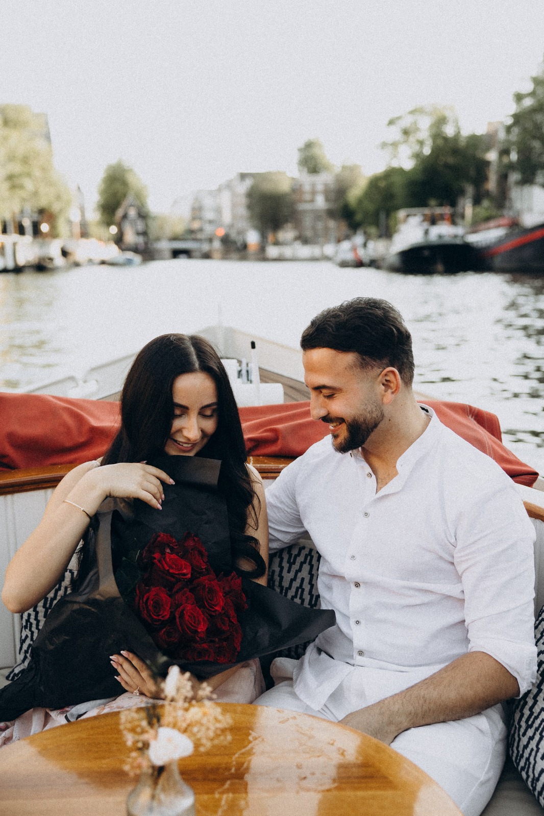 Pareja con un ramo de rosas rojas en un barco privado de los canales de &Aacute;msterdam