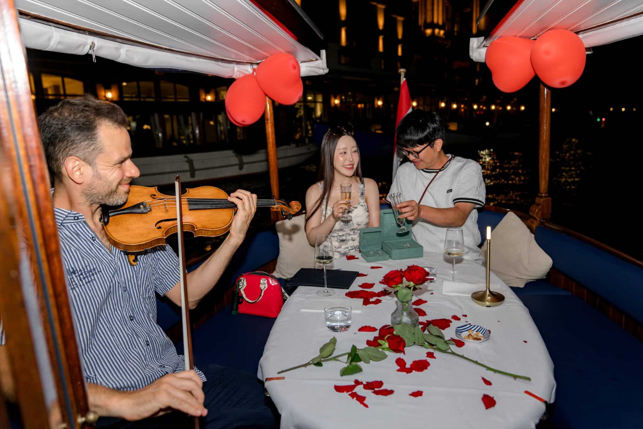 Violinista tocando a bordo de un barco privado de &Aacute;msterdam con rosas, champ&aacute;n y globos